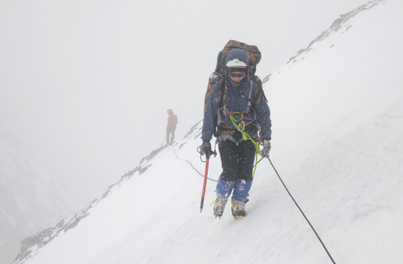 A two mountain climbers, girl and man, with rope on the slope. Ascent on Metallurg Peak. Altai Republic, Russiaのeditorial素材