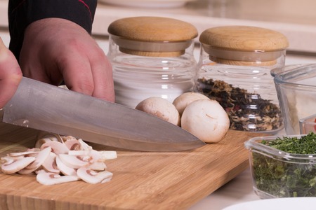 The chef cuts the mushrooms on a cutting Boardの写真素材