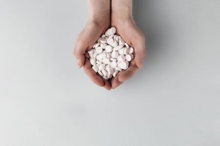Medication and white pills in the palms on a grey background. Top view. Copy spaceの写真素材