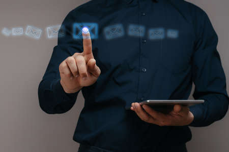 Man in a shirt clicks on the icon of an abstract envelope. Concept of mail and its sending. Copy spaceの写真素材