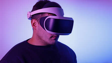 man in his thirties wearing virtual reality glasses, playing video games with a virtual reality...