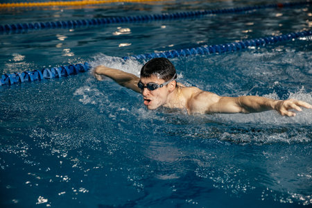 Swimming sports athlete swimmer swims in the pool, preparing for the race. Professional mens water sports for adults, engaged in cardio training in the water in the indoor pool. Panoramic banner.の写真素材
