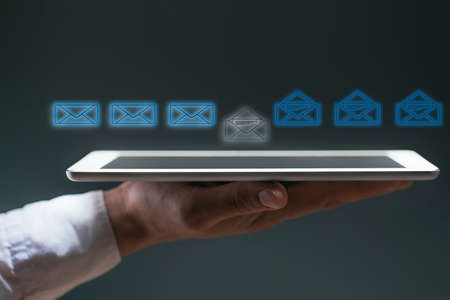Hand holds a tablet with icons of incoming messages and read messages in the form of a letter....