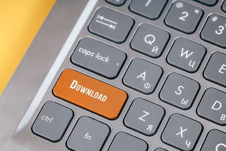 Orange boot key on a gray keyboard close-up. Button for downloading data from the Internetの写真素材