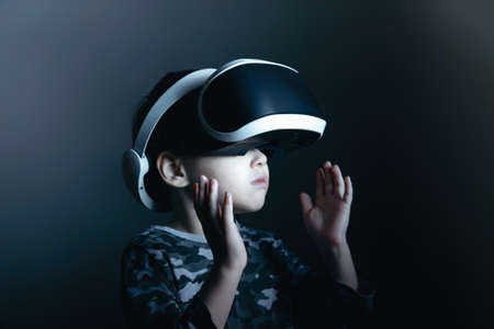 Close-up of a small five-year-old boy playing with virtual reality glasses. 3D gadget technology....