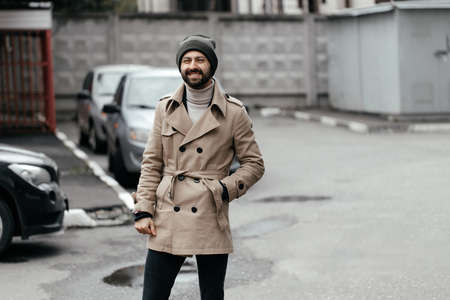 An image of a handsome young bearded man walking down the street and looking at the camera.の写真素材