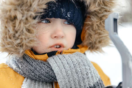 close-up of a baby in a winter red jacket with a fur hood. looks awayの写真素材