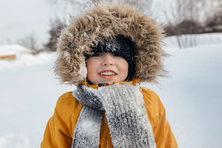 Close-up, image of a happy child in a hood in winter looking at the cameraの写真素材