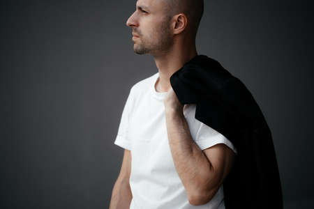Image of a handsome bald man in a white T-shirt on a gray background