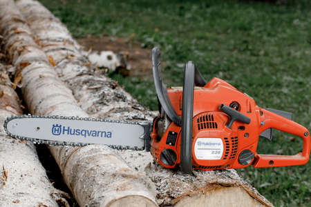 Kirov, Russia - 09.10.2020 Husqvarna 236 chainsaw stands on logs. global brand of garden equipmentのeditorial素材