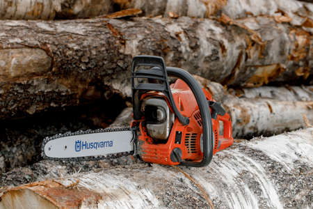Kirov, Russia - 09.10.2020 Husqvarna 236 chainsaw stands on logs. global brand of garden equipmentのeditorial素材