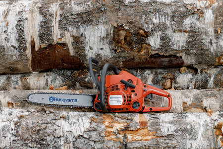 Kirov, Russia - 09.10.2020 Husqvarna 236 chainsaw stands on logs. global brand of garden equipment