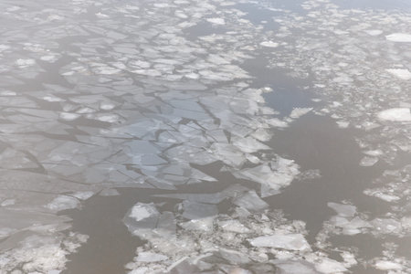 Ice fragments floating on a calm water surface, showcasing a mix of clear and cloudy ice in a...