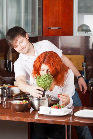 A young man presents potted thyme to his girlfriend while she eats strawberry and ready to cookの写真素材