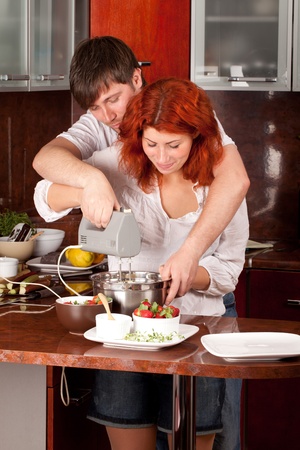 A young man helps his girlfriend in making pastryの写真素材