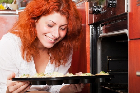 Young lady is about to put blueberry muffins into oven.の写真素材