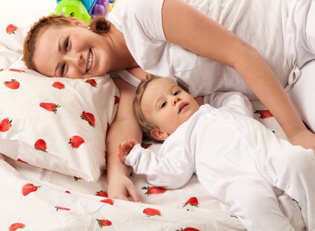 Mother and son are lying on the bed and looking at camera  Focus is on babyの写真素材