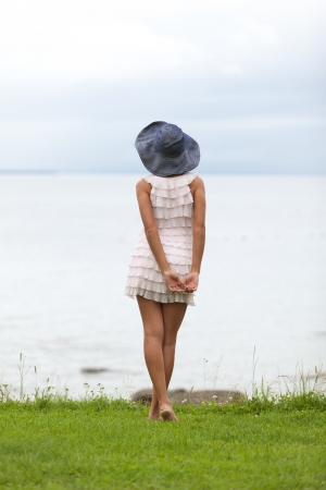 Girl in summer hat is waiting for the good weather to comeの写真素材