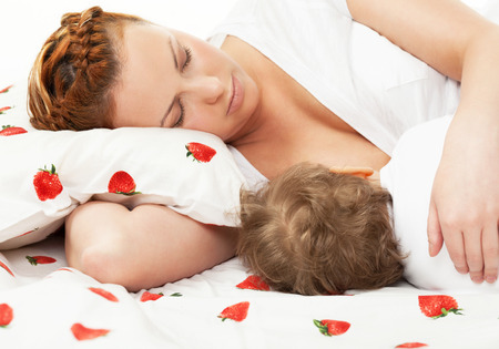 Mother breast feeding her child on the bedの写真素材