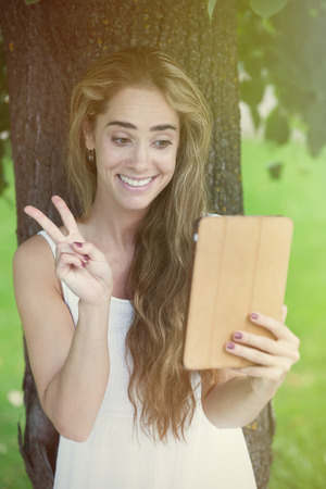 Young charming woman charming under the tree via table pcの写真素材