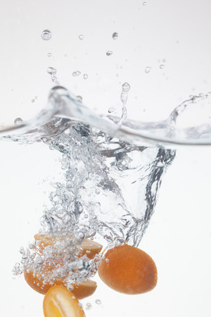 Ripe kumquat dropped into the clean waterの写真素材