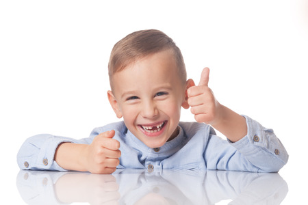 Laughing positive boy with the thumb up on isolated whiteの写真素材