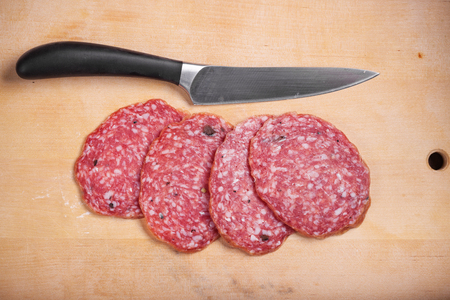 Slices of salami on a real desk with a knifeの写真素材