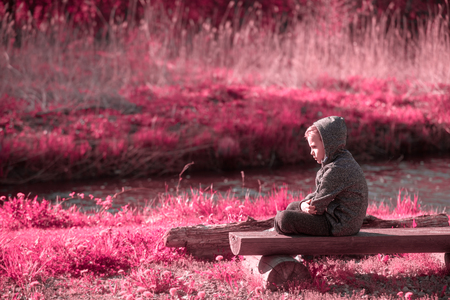 Vulnerable boy sitting at the river sideの写真素材