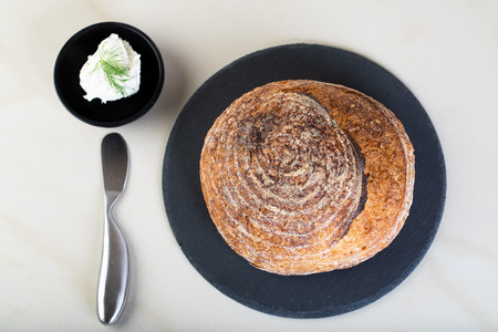 Wholewheat bread on black round plate with a serving of creamcheeseの写真素材