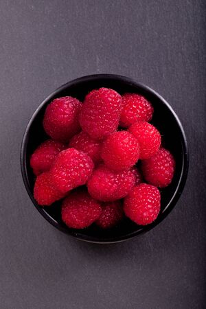 Raspberries in a black cupの写真素材