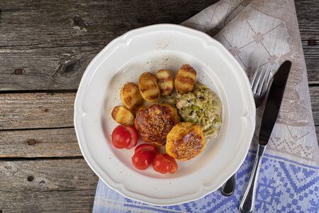 Lunch of fish cutlet with baby potatoes and leak sauce in a rustic settingの写真素材