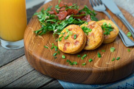 Egg muffins with bacon and cherry tomatoes served with fresh rocket salad on a wooden boardの写真素材