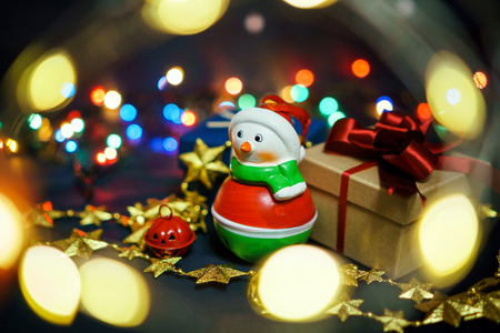 snowman with gifts on the background of garlands and lights