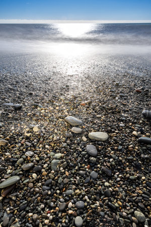 sea waves in the surf illuminated by the blinding sunの写真素材