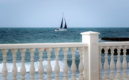 Sea view through the balustrade of the fence on the embankment sailboatの写真素材