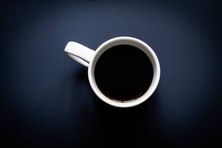Coffee mug on a deep blue background. Top view