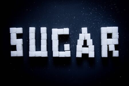 Cubes of refined sugar text on a blackの写真素材
