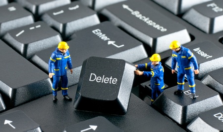 Team of construction workers working with DELETE button on a computer keyboardの写真素材