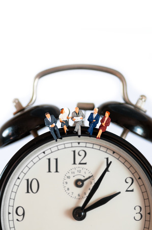 Businesspeople sitting on top of giant clock. Macro photo