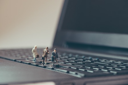 Miniature businessmen walking over the laptopの写真素材