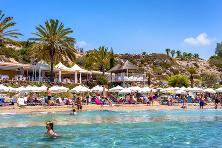 PAPHOS, CYPRUS - JULY 24, 2016: People relaxing on Coral Bay Beach, one of the most famous beaches in Cyprus.のeditorial素材