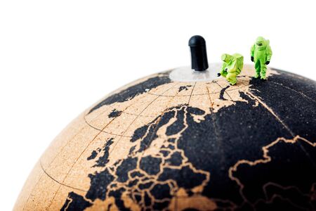 People in protective suits on top of the cork globe. Pandemic concept