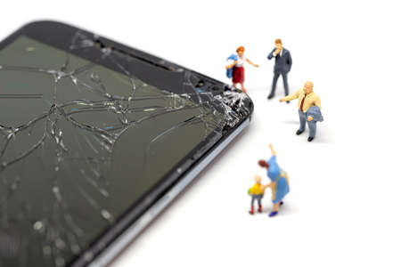 People figurines near broken mobile phoneの写真素材