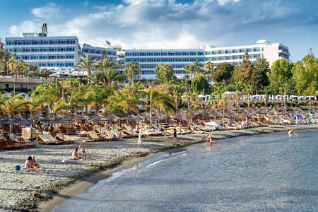 Limassol, Cyprus - June 24, 2018: People sunbathing at the beach with hotel on backgroundのeditorial素材