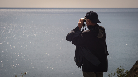 man looking through binoculars on the Bayの写真素材