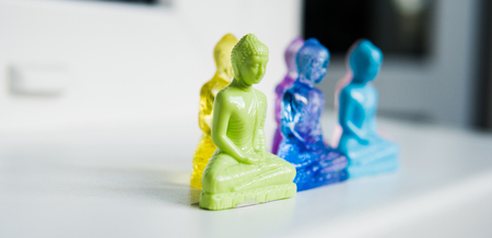 multicolored plastic buddha figurines on a light background. Modern Religions in the Worldの写真素材