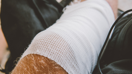 Bandaged leg after abrasion. Protect scratched body parts in travel.の写真素材