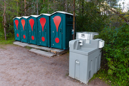 Eco-friendly, green, portable toilets stand in a row in the forest, with a hand wash basin and a toilet for campers nearby.の写真素材