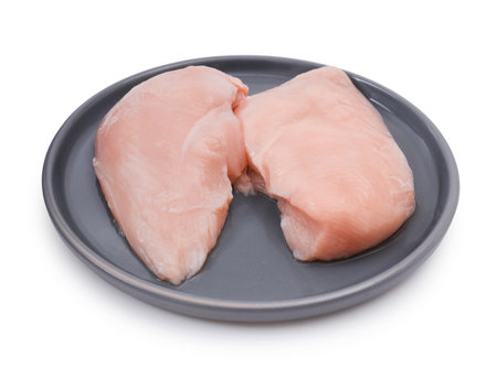 Fresh chicken fillet on a modern gray plate isolated on a white background. The fillet is raw and pink in color, showing its smooth texture.の写真素材