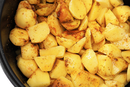 Close-up of raw potato chunks seasoned with spices inside a cooking pot, ready to be cooked for a savory meal. High quality photoの写真素材